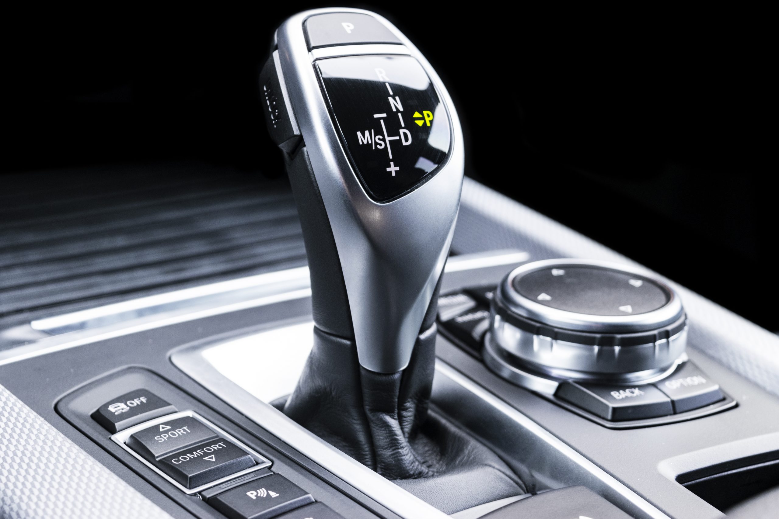Automatic gear stick of a modern car. Modern car interior details. Close up view. Car detailing. Automatic transmission lever shift. Black leather interior with stitching.